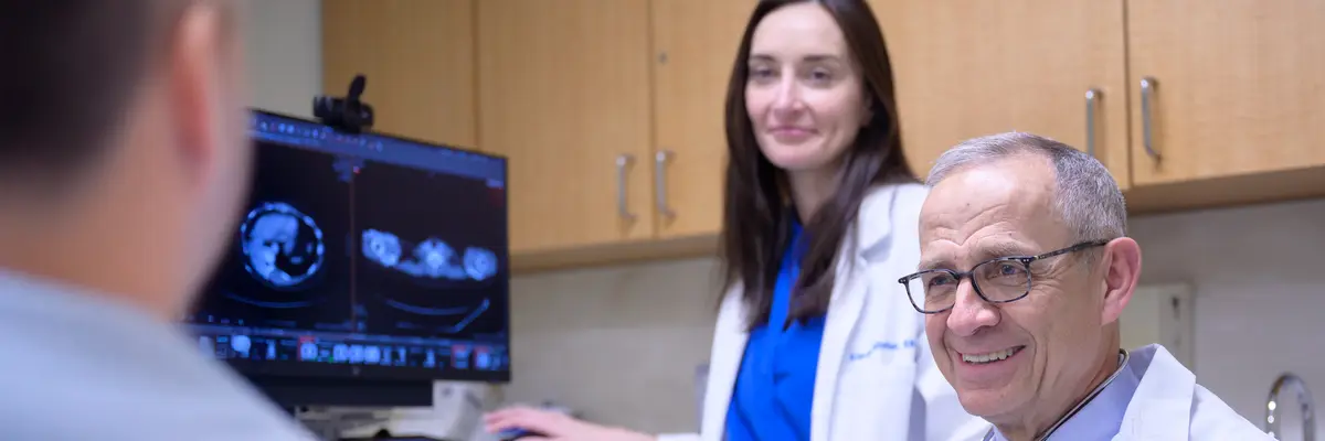 Colorectal surgeon Dr. Julio Garcia-Aguilar and a nurse in an exam room smile as they talk with an MSK patient