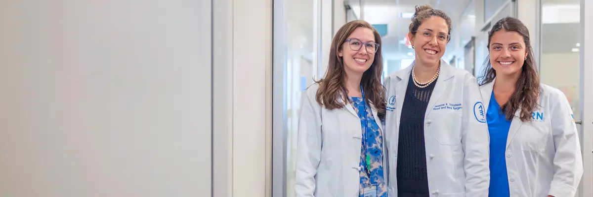 Head and neck surgeon Dr. Jennifer Cracchiolo with two female colleagues stand in a hallway at MSK. 