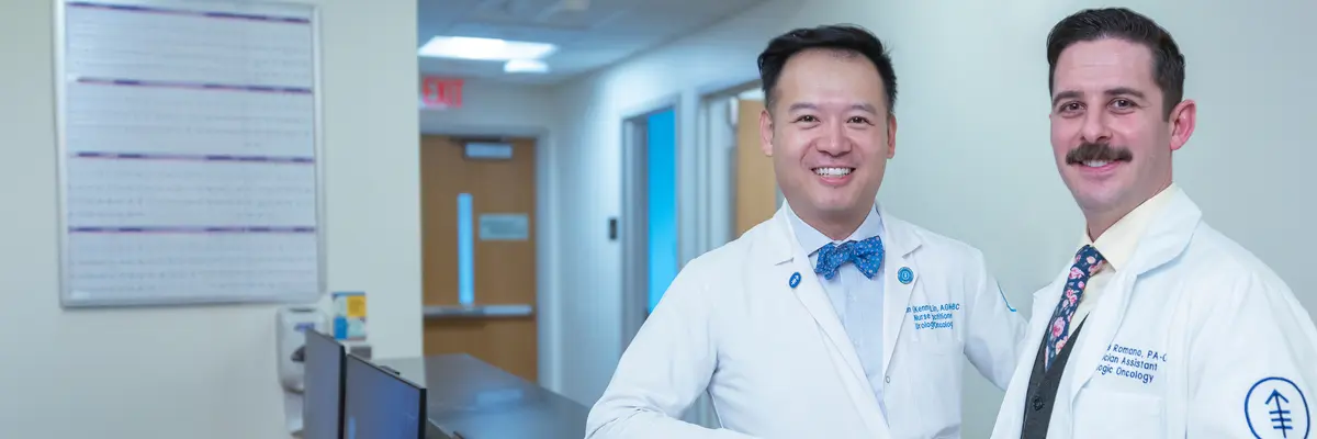 Nurse practitioner Xin (Kenny) Lin and physician assistant Nicholas Romano, who work with MSK’s Prostate Cancer Active Surveillance Program, stand together in an MSK reception area. 