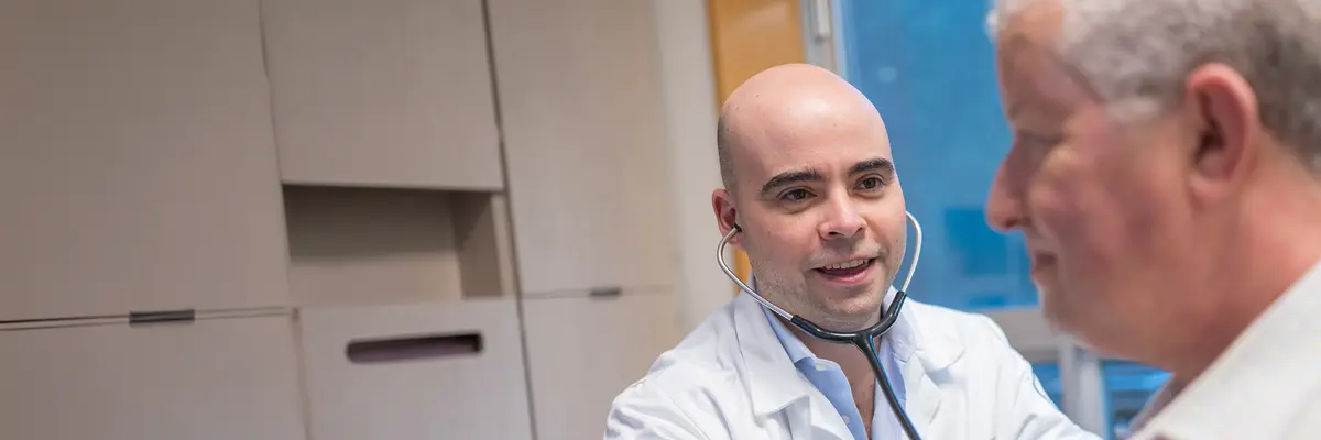 Genitourinary medical oncologist Dr. Salomon Tendler examines his patient with a stethoscope. 