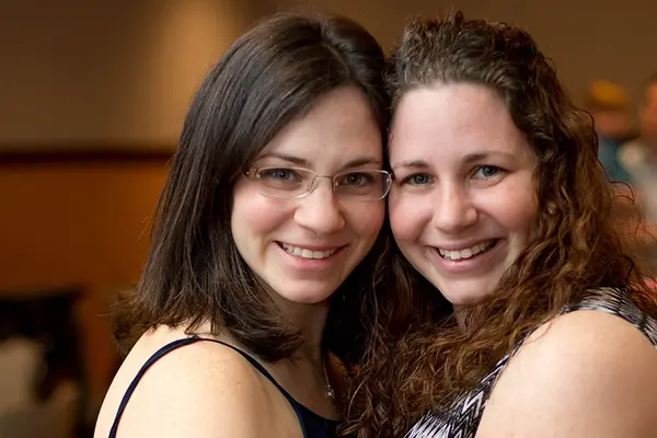Image of 2 sisters hugging and smiling at the camera 