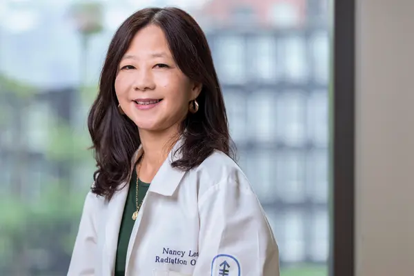 Radiation oncologist Dr. Nancy Lee, smiling and wearing a doctor’s white coat, treats patients at MSK in New York City 
