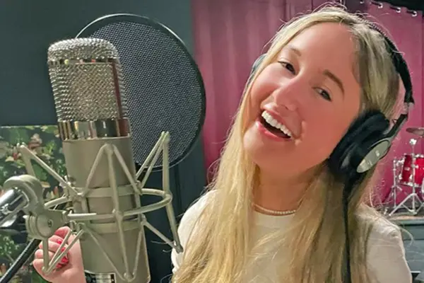 Thyroid cancer survivor Annabel Gutherz, treated for cancer at MSK, is singing in front of a microphone in a recording studio.   