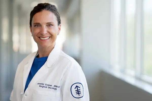 Jennifer Cramer, smiling, stands in a hallway at MSK. 