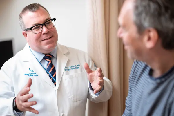 Dr. Donahue gestures with his hands as he talks with his patient in an MSK exam room.  