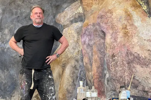 Prostate cancer survivor and painter Alexandros Washburn stands next to his artwork. 