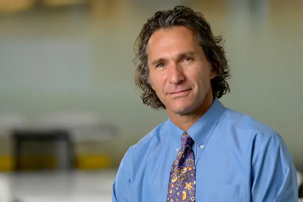Research scientist Dr. Andrew Vickers, in shirt and tie, is standing in an MSK conference room.  