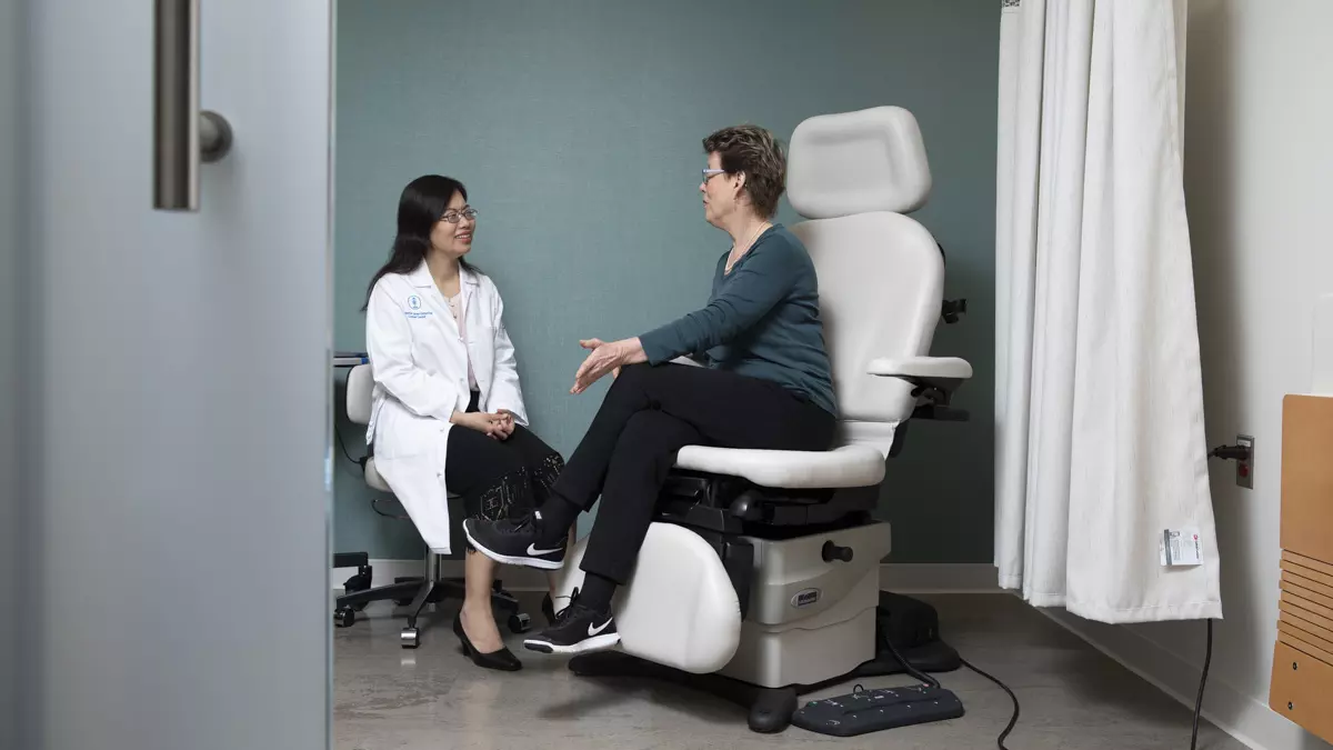 Breast medical oncologist Rui Wang (left) listens to a patient during an exam. 