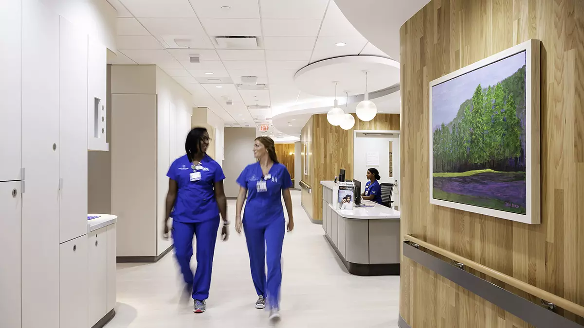 Two registered nurses walk down a hallway in a section that has 16 private inpatient rooms for people who need an overnight stay for treatment.
