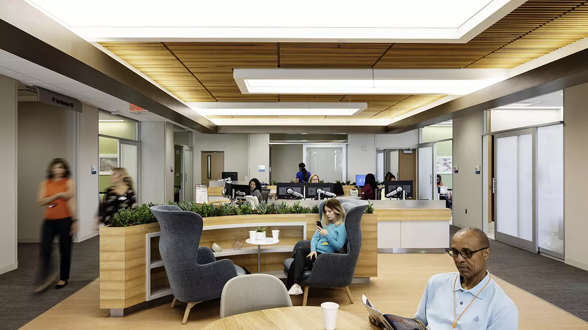 Several people relax in a large comfortable room outside private infusion rooms in a treatment area at MSK Koch. 