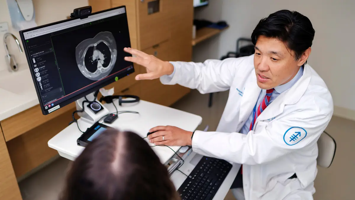 Head and neck medical oncologist Dr. Alan L. Ho in New York City points to an imaging scan on a computer monitor during an exam with his patient. 