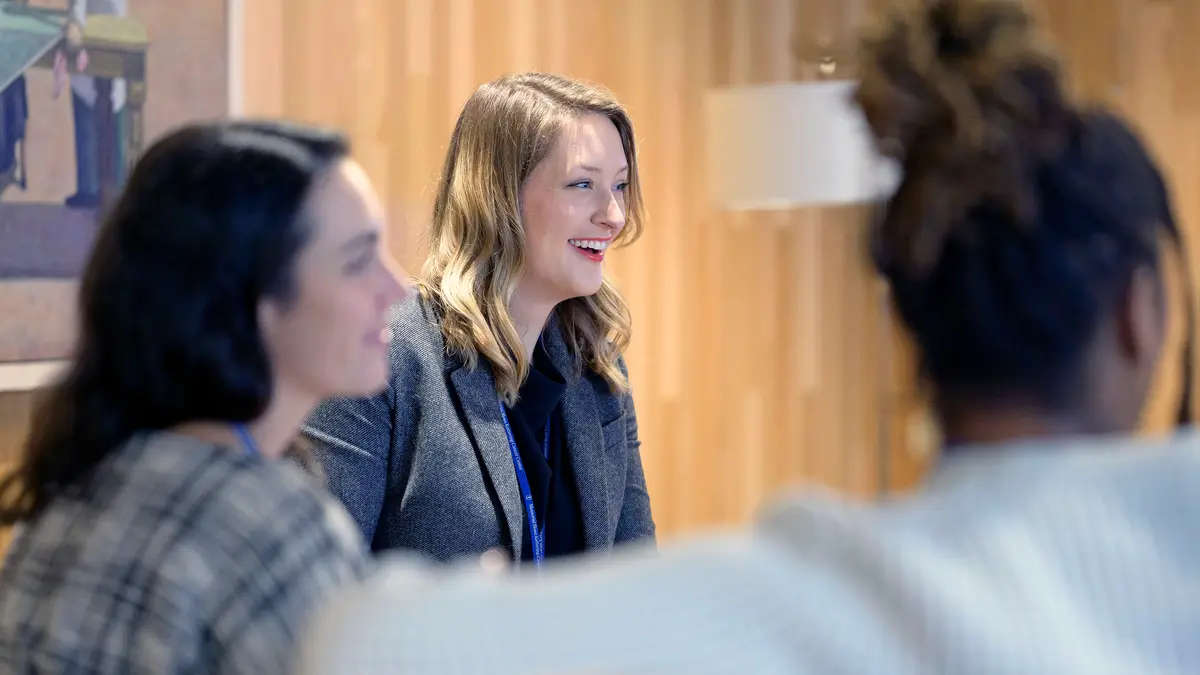 Three female MSK clinical social workers sit together, talking and smiling. 