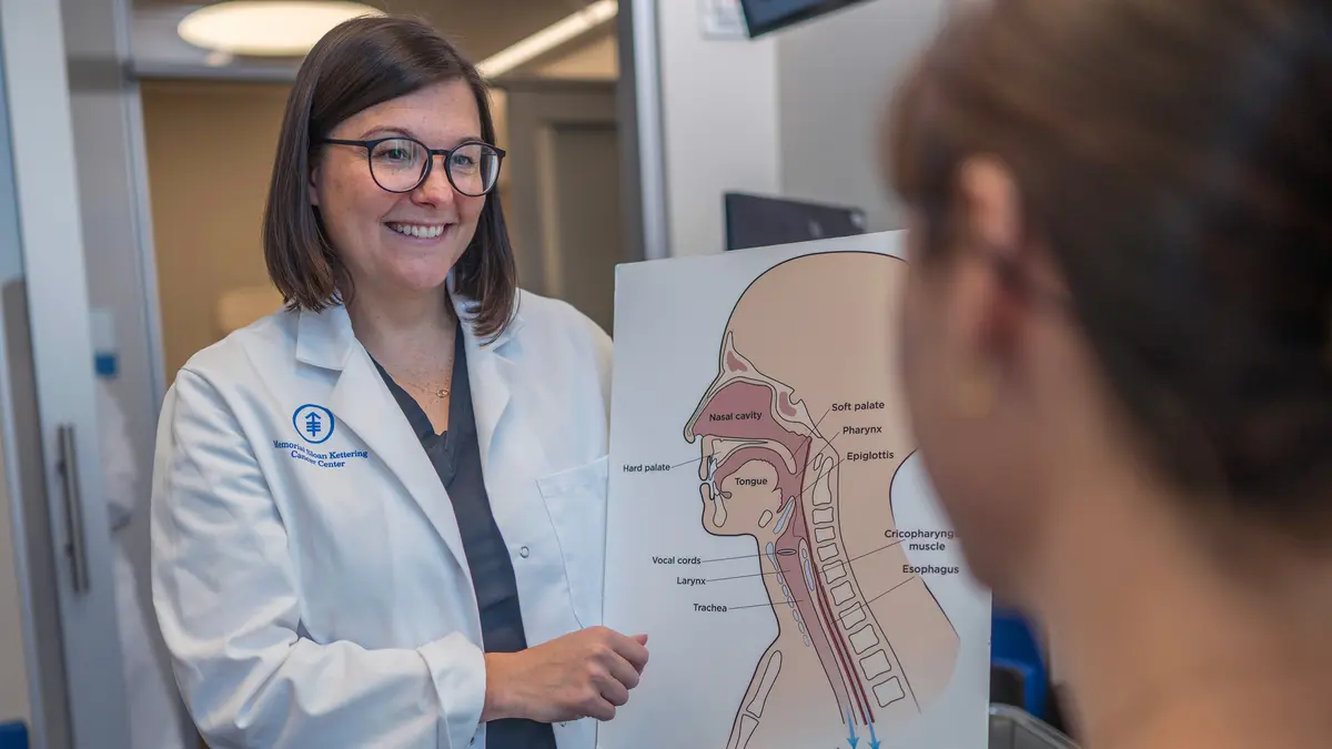 Speech pathologist Louise Cunningham holds a large illustration of the parts of the head and neck to show her patient.  