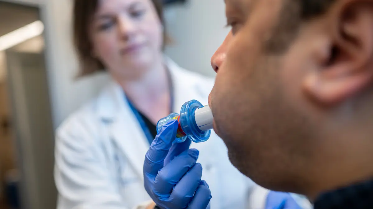 An MSK patient uses an Expiratory Muscle Strength Trainer device with a speech pathologist. 