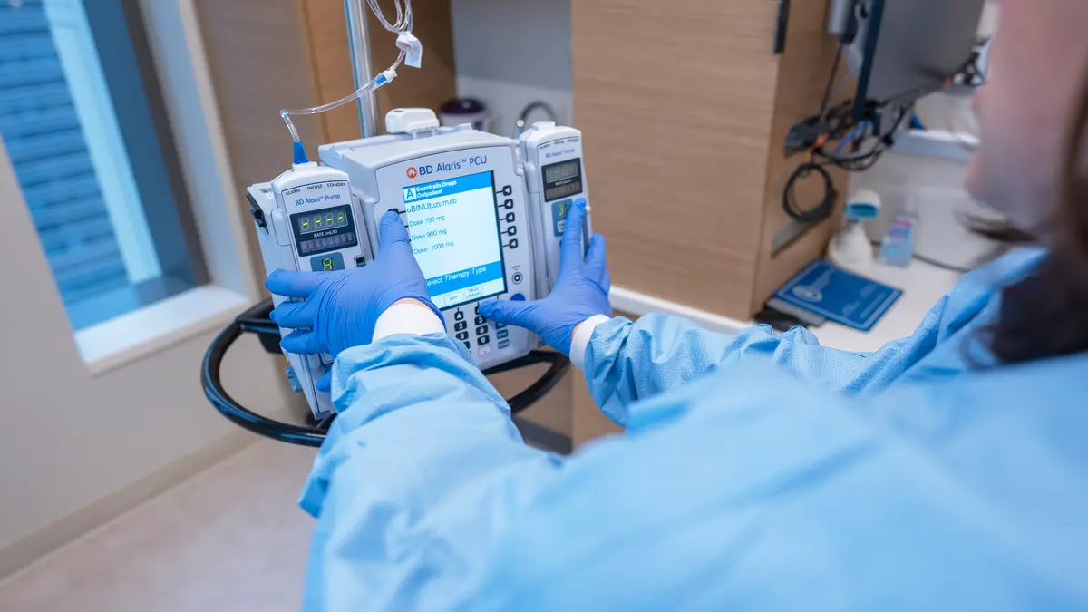 A nurse's hands adjust chemotherapy treatment equipment at an MSK infusion site.