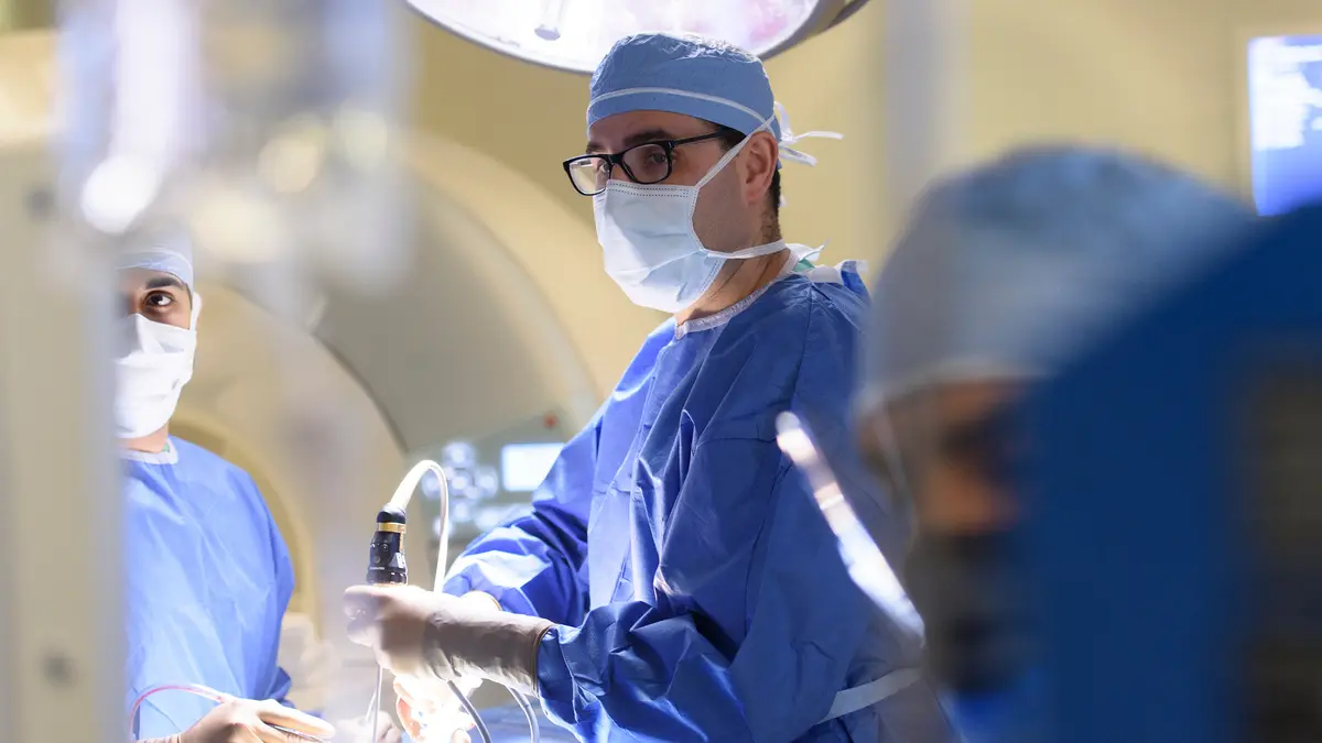 Head and neck surgeon Dr. Marc A. Cohen, wearing surgical scrubs, is with 2 MSK colleagues during a surgery. 