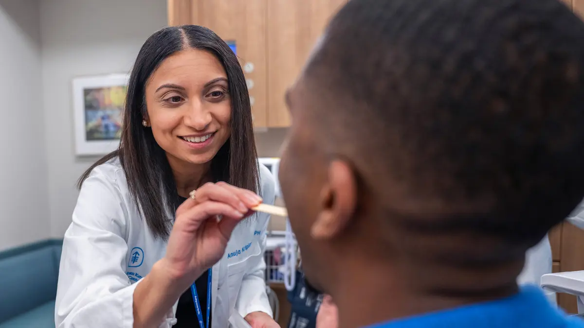 An MSK doctor uses a tongue depressor to examine the throat of her patient. 
