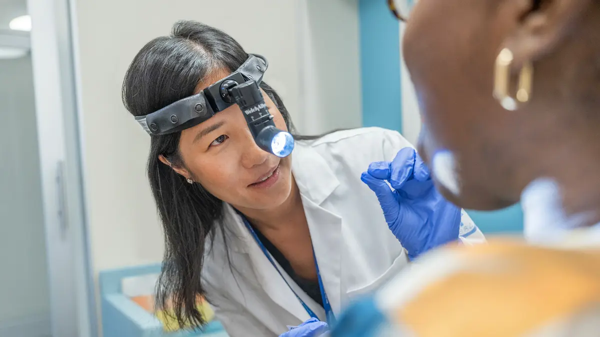 An MSK speech pathologist wears a headlamp as she examines the mouth of her MSK patient. 