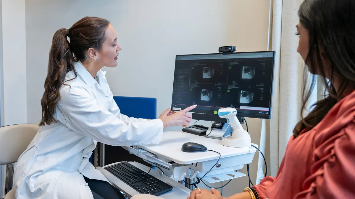 A nurse practitioner points to a screen as she reviews a modified barium swallow study with her patient. 