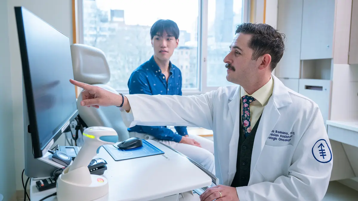 Nicholas Romano points to a monitor in an MSK exam room. 