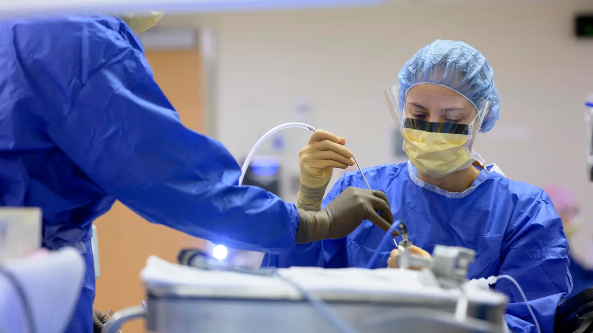 Two MSK surgeons wearing protective gear hold surgical instruments in the operating room.