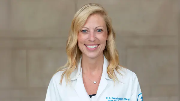 Headshot of physician assistant Christina Swartzwelder, smiling, with shoulder-length blonde hair, wearing a white exam coat.